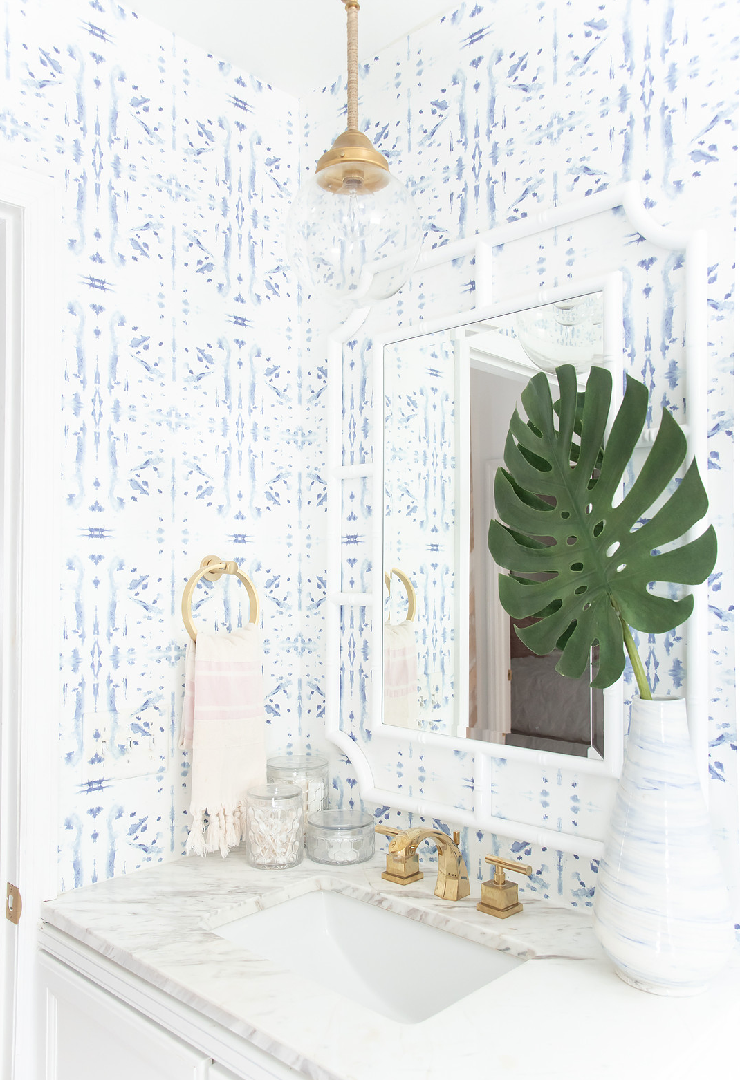 vibey apartment, drop pendant bathroom vanity white bamboo mirror white rattan mirror bathroom brass and white bathroom blue dot wallpaper